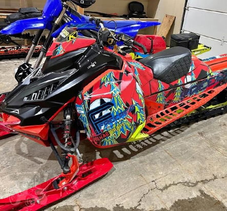 Red snowmobile and blue dirt bike